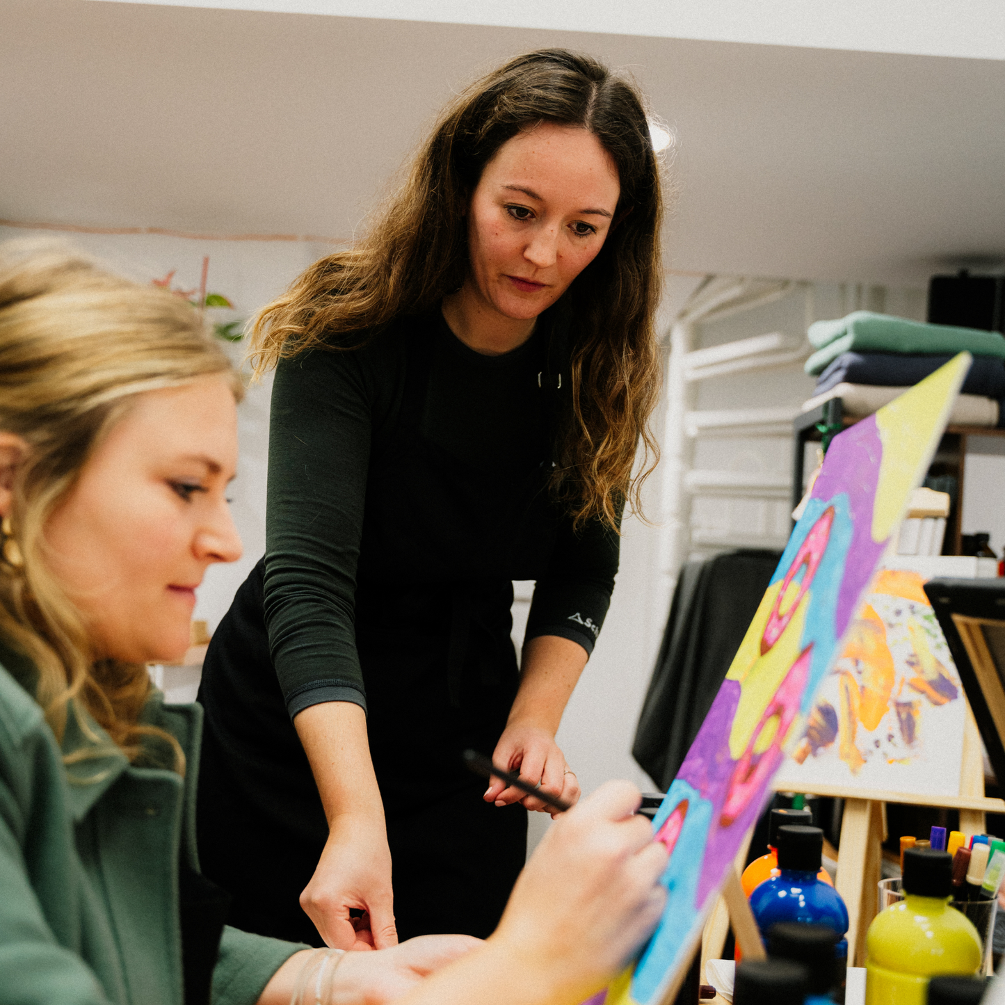 Im Kreativstudio München bemalen die Kursteilnehmer Gemälde mit Acrylfarbe.