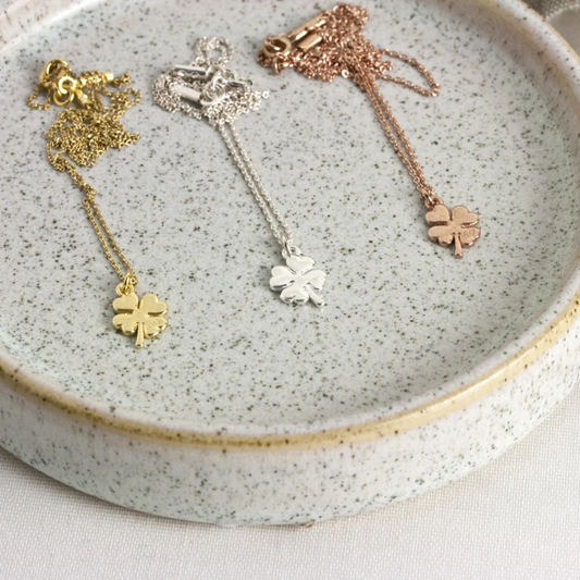 Drei Halskettchen in den Farben Gold, Bronze und Silber liegen auf einem Stein.