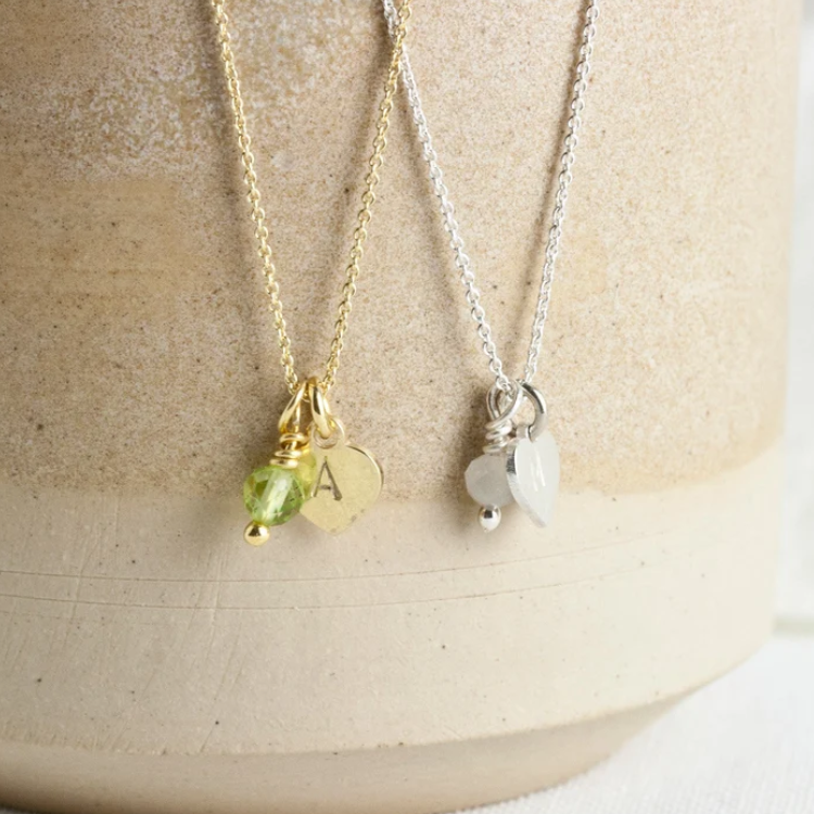 Zwei Kettchen aus Gold und Silber hängen an einem Stein.
