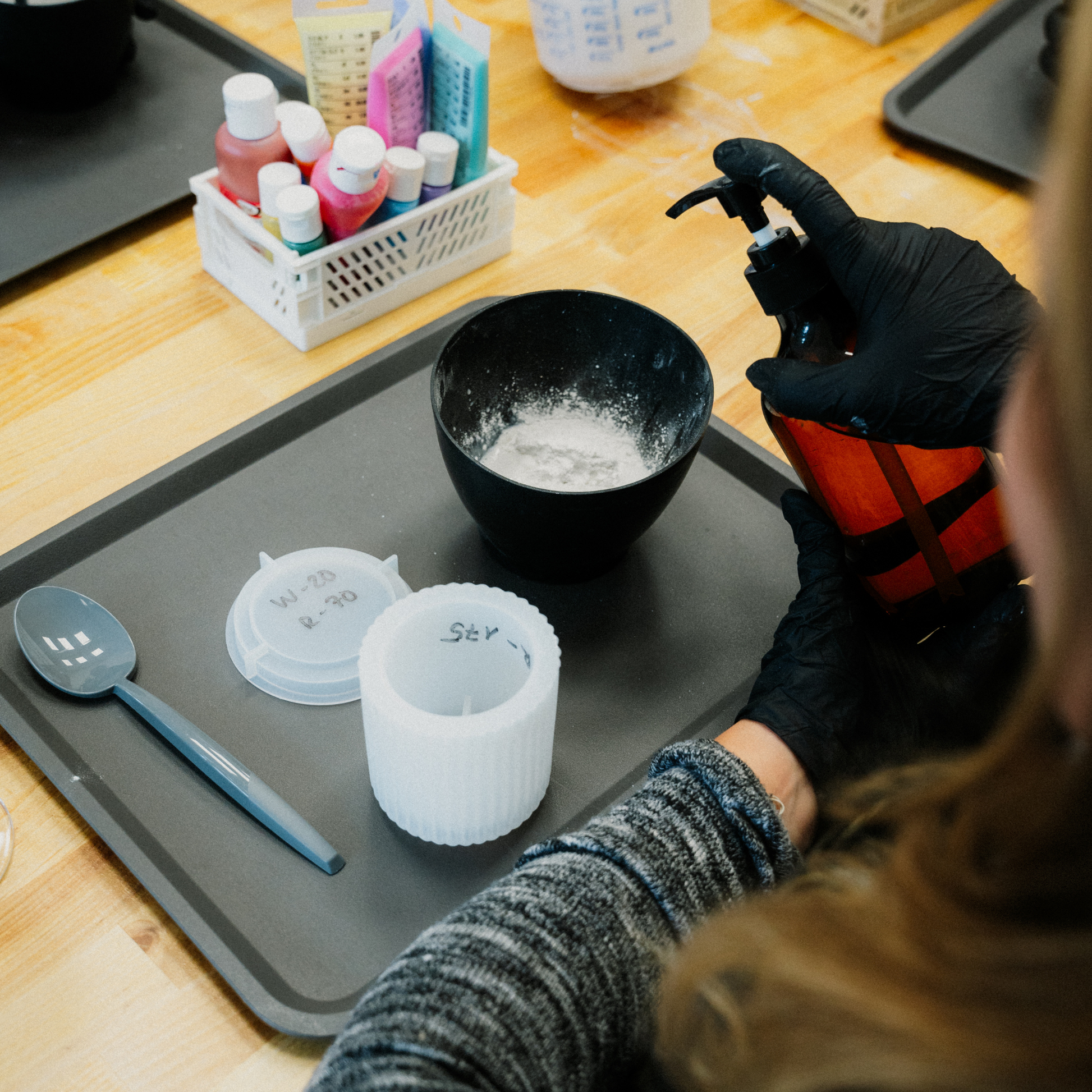 Eine Teilnehmerin eines Betondekoration Workshops gibt gerade einen Wasser zum Betonpulver auf einem schwarzem Tablett