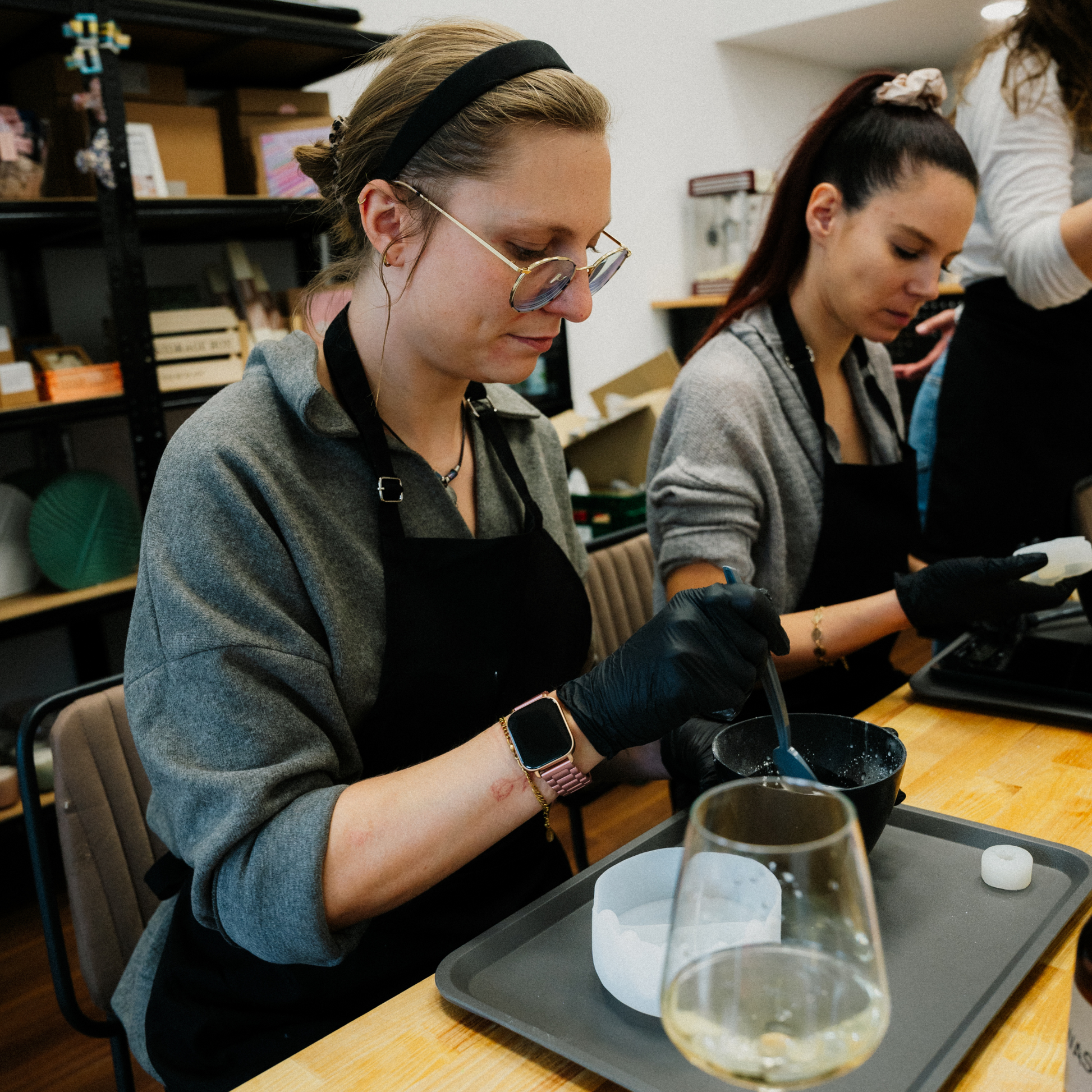 Zwei junge Teilnehmerinnen sitzend nehmen an einem Beton Workshop im Kreativstudio München teil. Sie rühren gerade den Beton an.