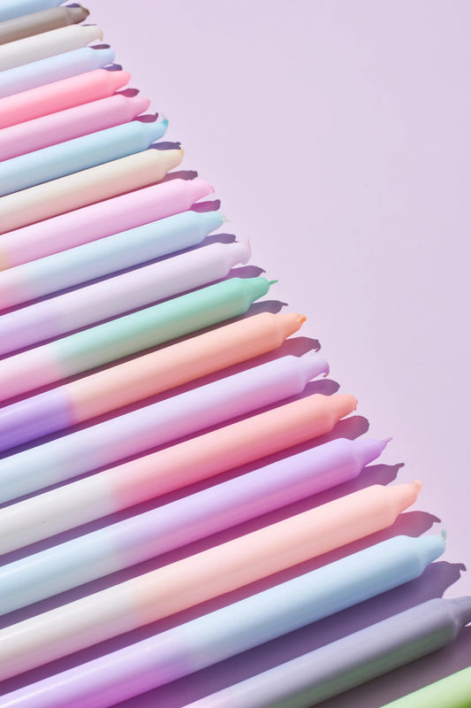 Viele bunte gedippte Kerzen in einer Reihe schräg liegend.