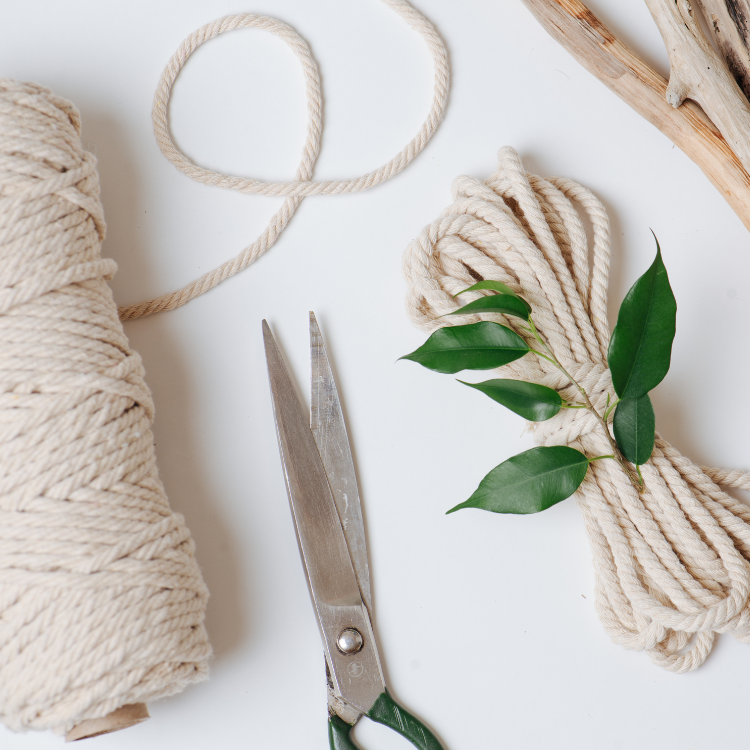 Schere, Wollgarn und Grünzeug liegen auf einem Tisch.