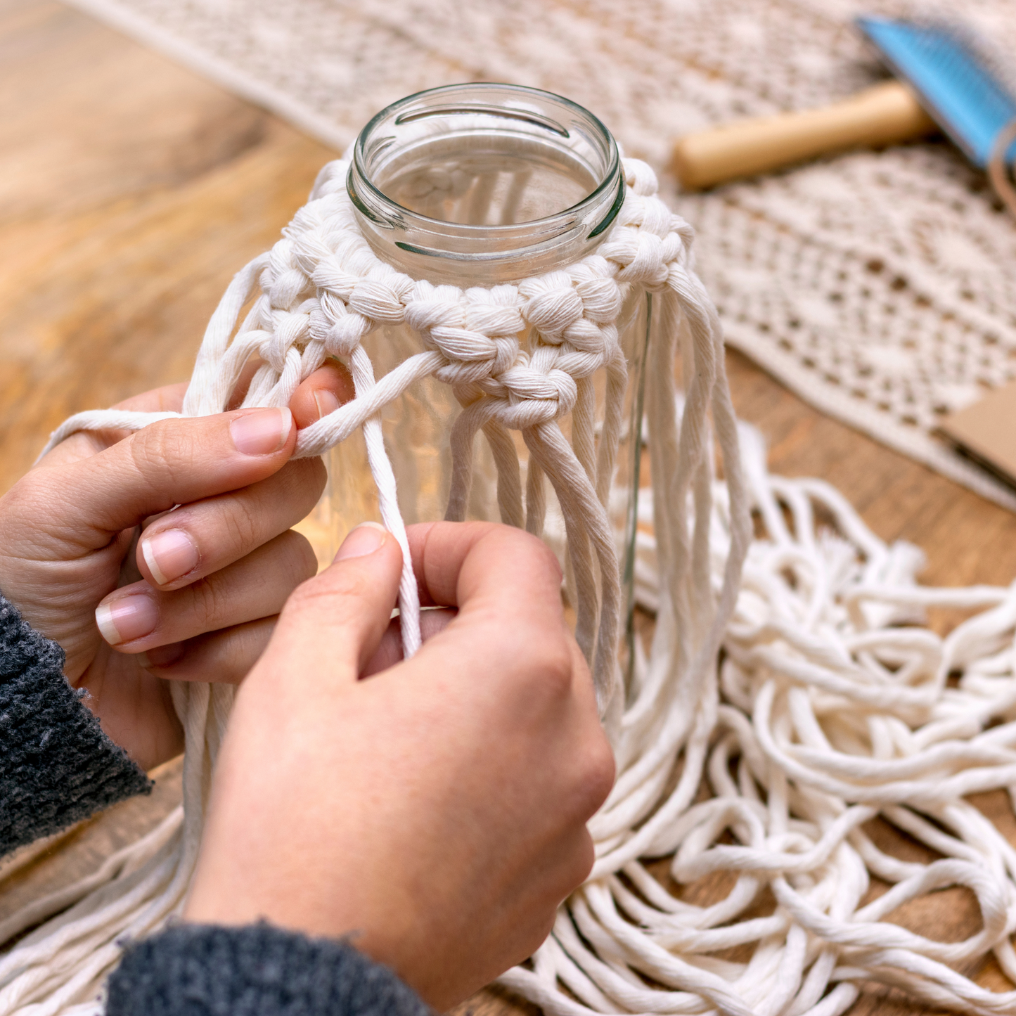 Zwei Hände knüpfen ein Makramee an ein Windlicht im Workshop Makramee Windlicht und Kerzen dippen im Kreativstudio München.