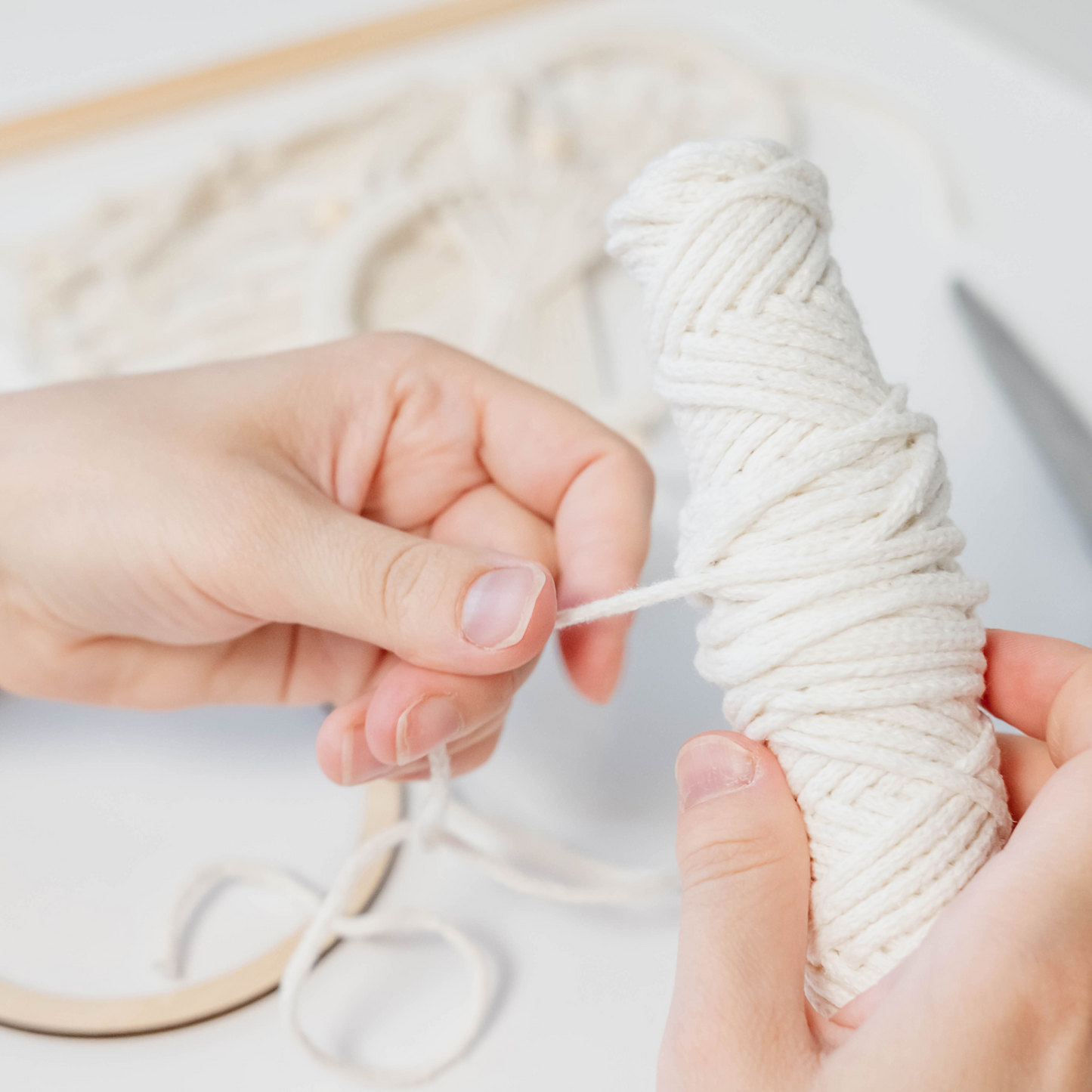 Zwei Hände knüpfen ein Makramee aus Wolle in einem Workshop.