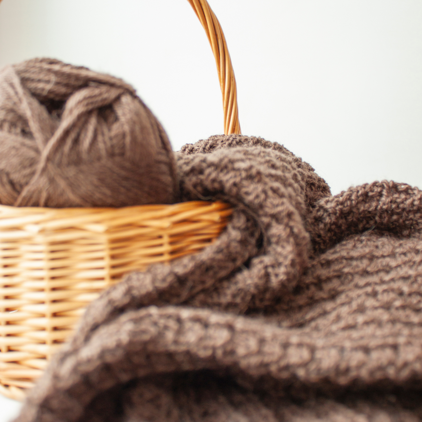 Ein Bastkorb mit Strickutensilien und einem selbstgestrickten Wollstück.
