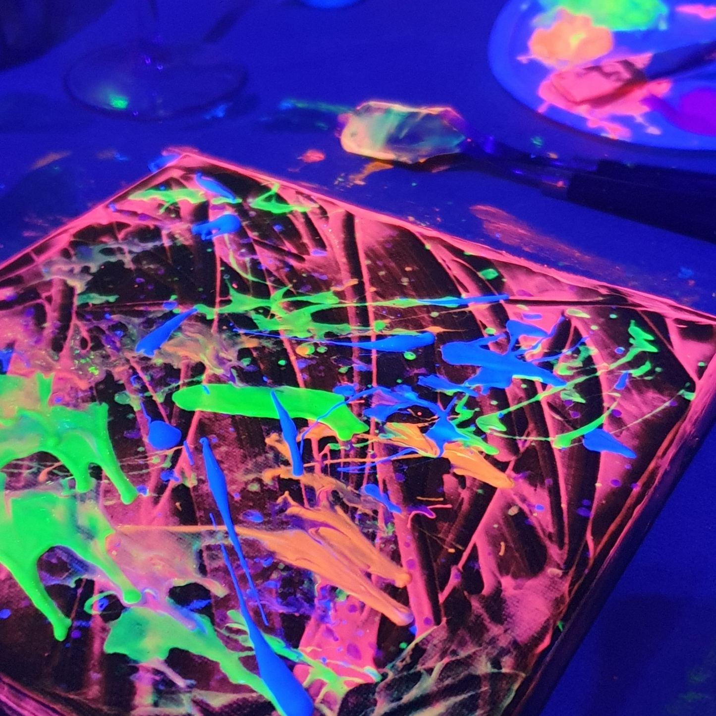 Leuchtendes wildes Gemälde mit UV-Farben bei Technomusik erstellt.