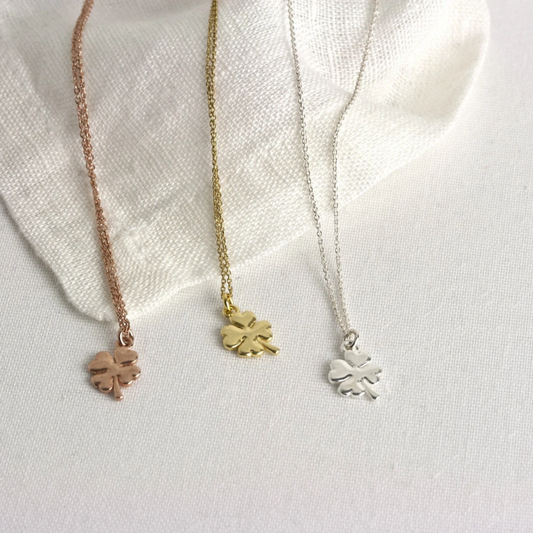 Drei auf einem Leinentuch liegende Halskettchen mit Anhänger. Bronze, Gold und Silber.