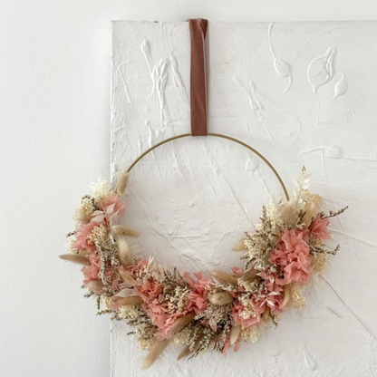 Blumenring aus einem dünnen Drahtgestell mit roten und beigen Trockenblumen und braunen Aufhänger