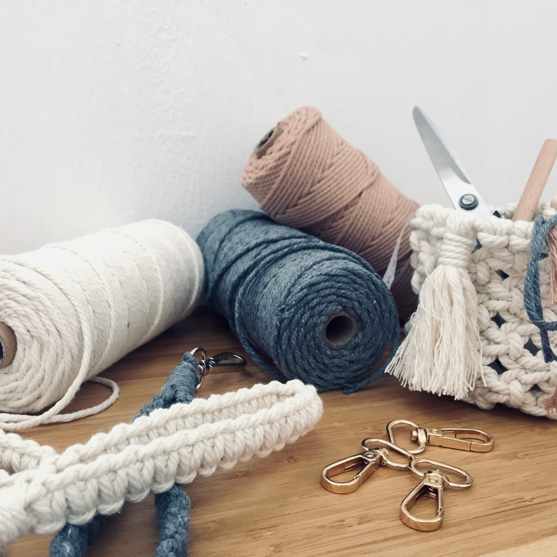 Verschiedene Farben von Garnen liegen mit Schere und Verschlüsse auf einem Tisch.