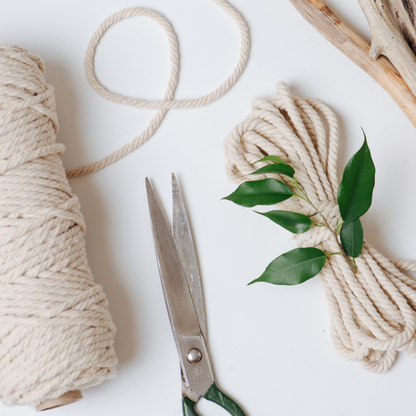 Schere, Wollgarn und Grünzeug liegen auf einem Tisch.