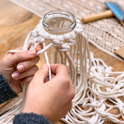 Zwei Hände knüpfen ein Makramee an ein Windlicht im Workshop Makramee Windlicht und Kerzen dippen im Kreativstudio München.