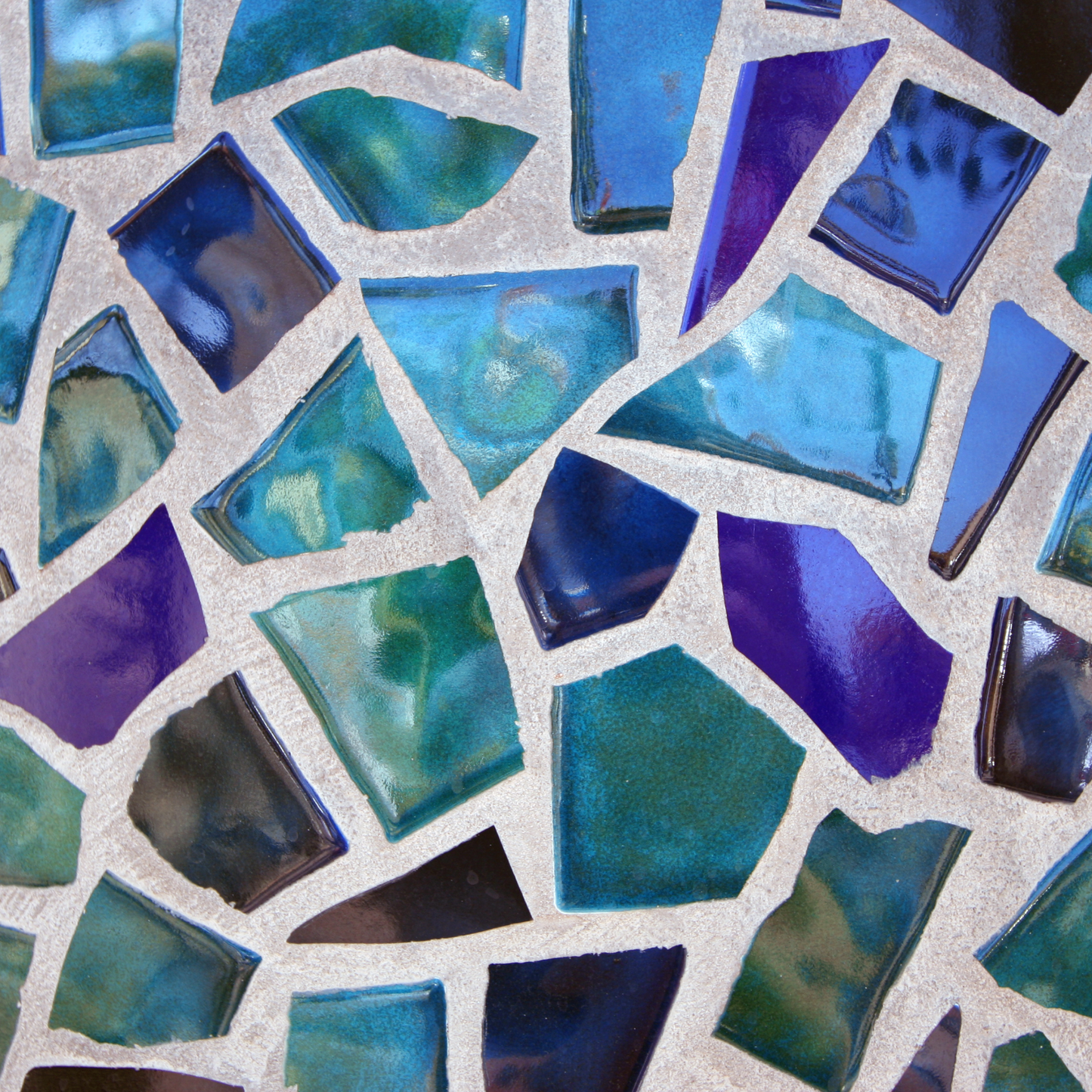 Mosaiksteine aus Glas eingearbeitet in Beton, schillernd in verschiedenen Farben.