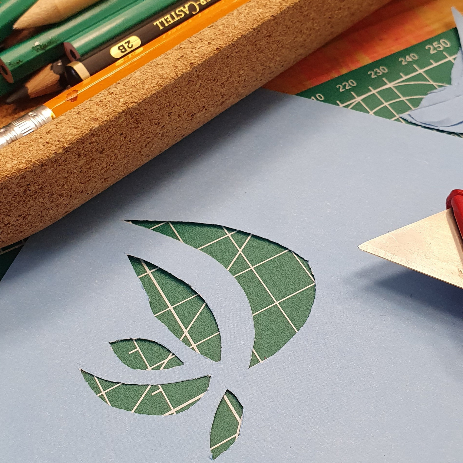 Nahaufnahme von einem bearbeiteten Papier mit Formen auf einem Schreibtisch liegend. Neben Schreibzubehör.