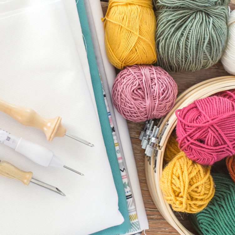 Verschiedenfarbige Wolle liegt neben einem weißen Leinentuch. Punch Needle Workshop.