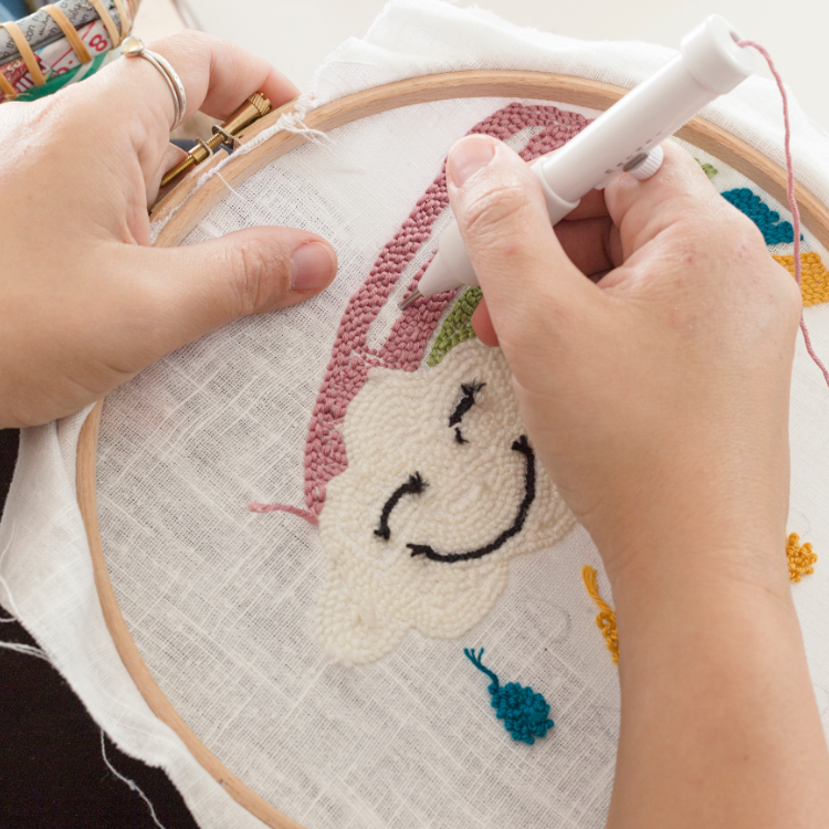 Eine Person stellt einen Kissenbezug mit der Punch Needle Technik im Kreativstudio München her. 