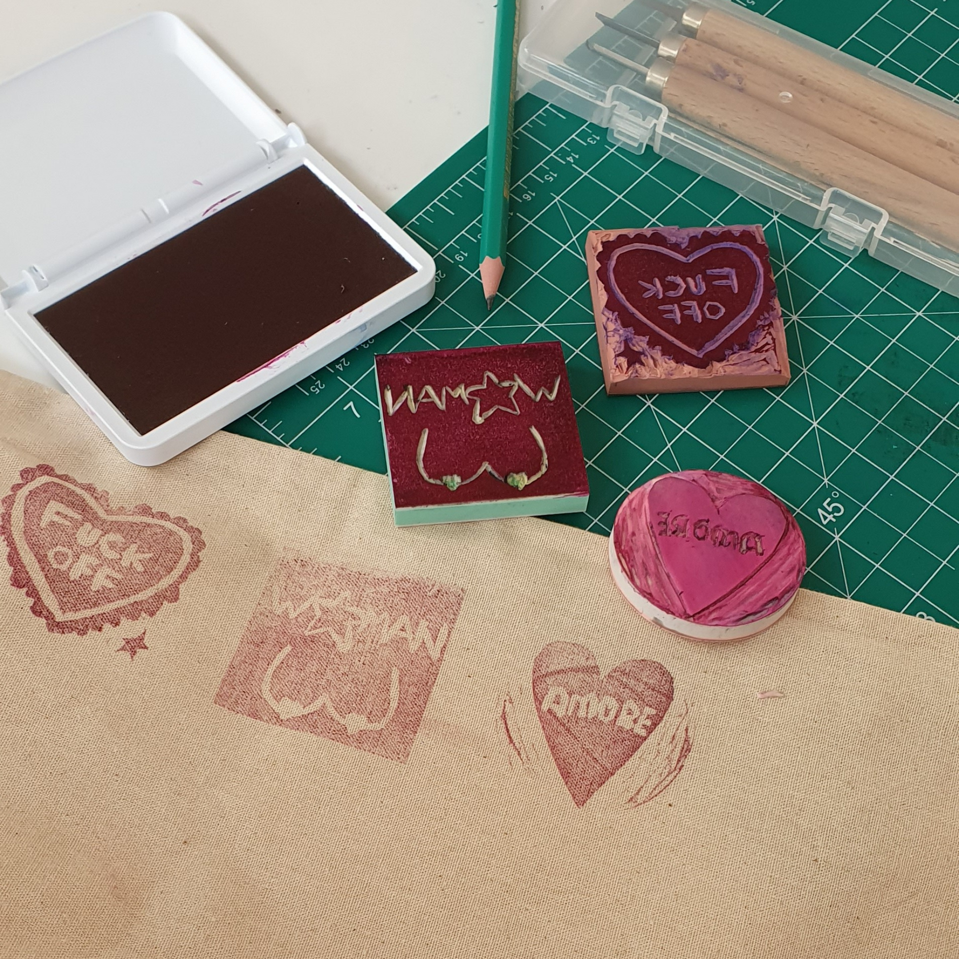 Stempelkissen, geschnitzte Stempel und Zubehör liegen auf einem Tisch.